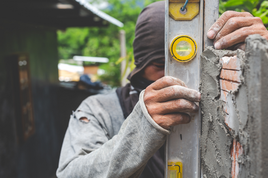 Skilled mason aligning a brick wall using a spirit level, ensuring precision and structural integrity during masonry construction.